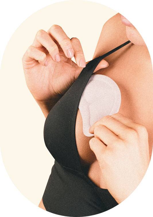 Person wearing a black bra with a silicone pad on a beige background